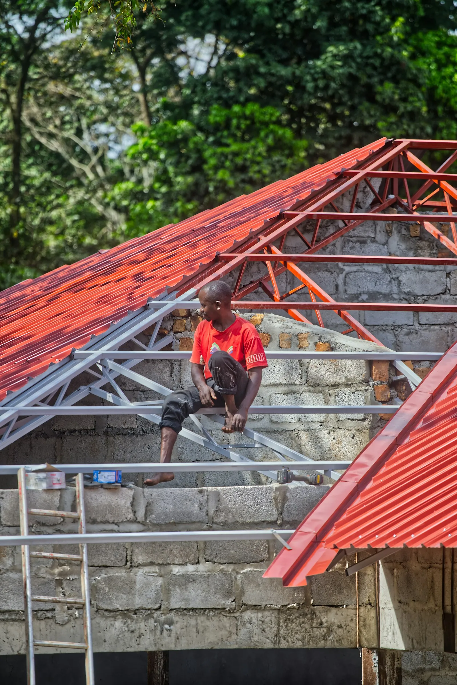Pekerja memasang genteng metal merah baru pada rangka atap di Mustika Jaya